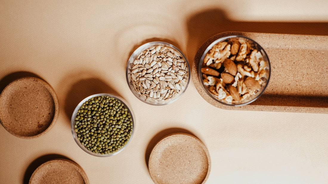 Bowls of seeds and a jar of nuts on a counter